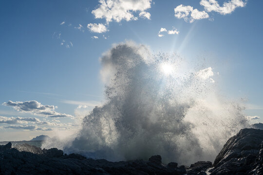 Waves crashing at cliff in sunlight. High quality photo