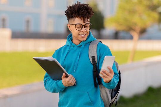 Walking student reading tablet and holding phone