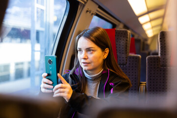 Portrait of contemplative brunette woman travelling by express train, sitting on soft comfortable...