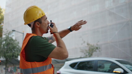 Hardhat man giving instructions using walkie-talkie in construction site closeup
