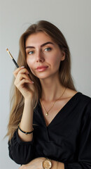 Obraz premium beautiful woman with long straight hair and makeup holding an eye shadow brush as she shows it to the camera