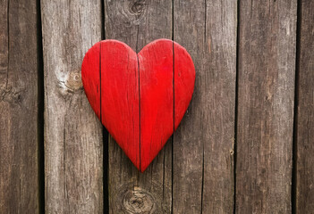 Bright red heart as a symbol of love and friendship on wooden wall or fence background