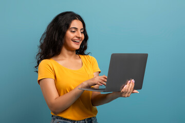 Happy woman holding and looking at laptop