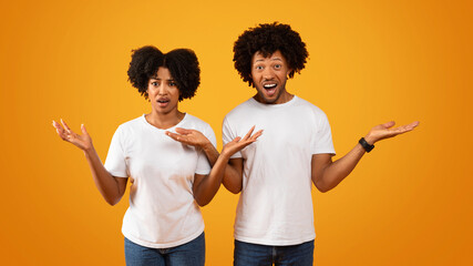 Shocked african american couple gesturing and grimacing on yellow - obrazy, fototapety, plakaty