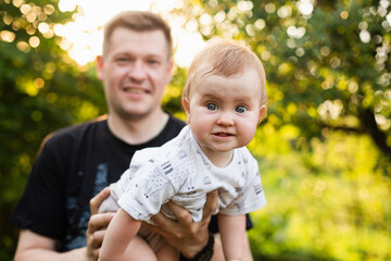 Fototapeta premium Dad holds his little daughter in his arms, summer sunset, An emotional child