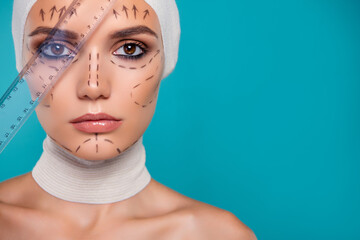 Photo of lady in medical bandage over cyan color background measure with ruler facial proportions