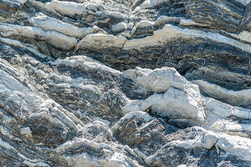Nature force compressed prominent cracked rock layers structure formation details, in various shapes, colors, thicknesses, at south central coast of Crete, Greece. Nature Geological science concept.