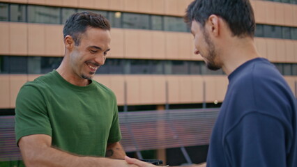 Cheerful postman delivering box to customer in modern business district closeup