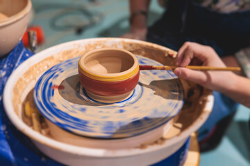 Fototapeta na wymiar Pottery lesson master class for kids children, process of making clay pot on pottery wheel, potter hands creating ceramic crockery handcrafts, ceramist molding and painting jar or vase