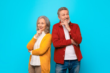 Thoughtful senior husband and wife standing back to back, studio