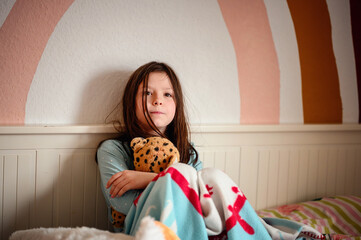 A girl's laughter fills the room as she clutches a plush leopard, against the playful backdrop of a...