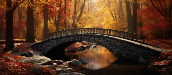 Rolgordijnen A painting depicting a wooden bridge spanning over a gentle stream in an autumn forest, with fallen golden leaves carpeting the scene. The bridge leads the eye through the tranquil forest. © pngking