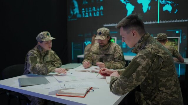 Group of security squad in control center. Military headquarters surveillance officers cyber police briefing at the table in office, checking paper documents.