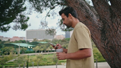 Relaxed tourist walking park holding beverage takeaway close up. Guy strolling 