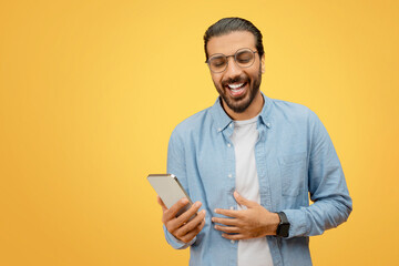 Man laughing with phone, casual denim