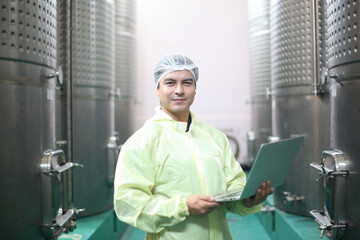 Winemaker working in modern large winery factory drink industry  and he testing wine in a wine factory warehouse