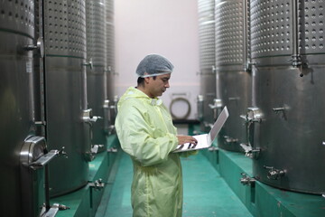 Winemaker working in modern large winery factory drink industry  and he testing wine in a wine factory warehouse