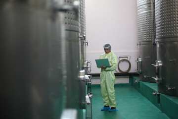Winemaker working in modern large winery factory drink industry  and he testing wine in a wine factory warehouse - 769182484