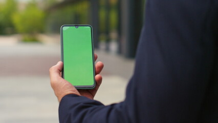 Closeup hand use green screen smartphone on street. Man in suit talking call