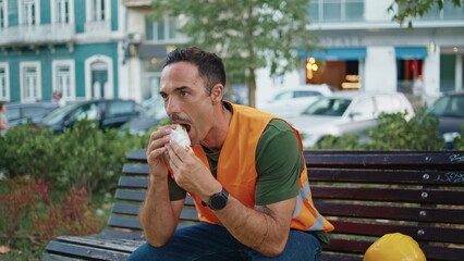 Relaxed builder resting break eating lunch street closeup. Man tasting sandwich