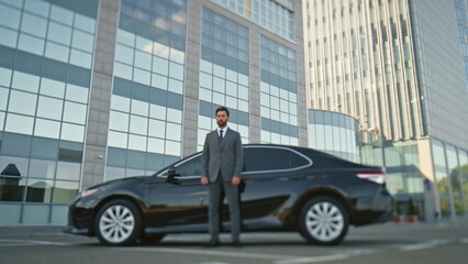Elegant driver standing car premium class on city district. Gentleman posing