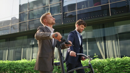 Two employees going downtown in morning. Smiling friends commute with scooter