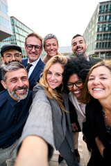 Vertical selfie of a cheerful team of diverse business people in formal suit looking smiling at...