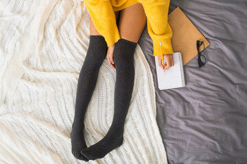 Girl sitting on bed and making notes to her diary