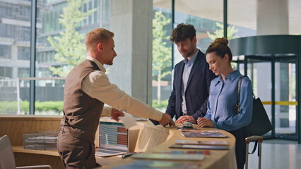 Hotel receptionist welcome guests at modern counter. Smiling man woman check in