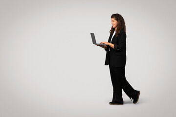 Businesswoman walking and using laptop