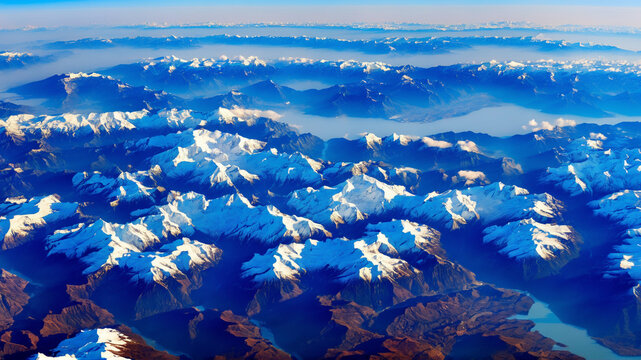 aerial view of a mountain range, possibly taken from an airplane. The mountains are covered in snow and ice, creating a stunning and majestic landscape