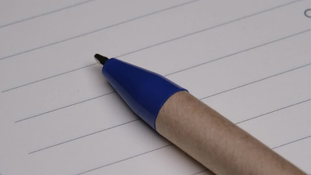 Macro detailed video of the ballpoint pen nib. On a lined notepad. Education and work life concept.