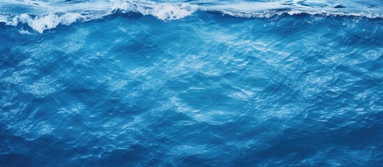 A captivating closeup shot of electric blue water with wind waves crashing onto the shore, showcasing the beauty of natural water resources