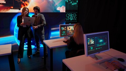 Earth control center, team monitoring galaxy on big screen. Group of people in mission center working on computers, observing flight and space data, discussing process.