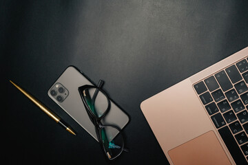Business layout with items for design. Phone, glasses, pen, laptop on the table. In a dark style,...