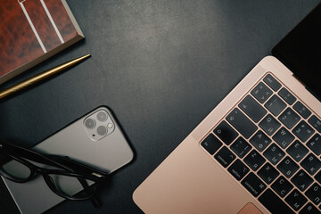 Business layout with items for design. Phone, glasses, pen, laptop on the table. In a dark style, there are object layouts on the table. Top view of items
