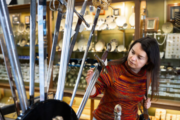 Young adult traveling woman choosing steel souvenirs of Toledo displayed in shop for sale