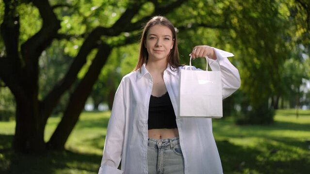 Campaign for environmental protection. A beautiful girl shows that you should use recycled paper bag and not plastic bags. A young woman looks at the camera and smiles