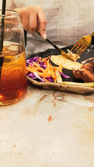 portrait of woman's hands enjoying dajaj mashwi, oven roasted chicken with tearing khubus (pita bread) with fork and knife on plate