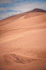 Vast sandy dunes stretch across the image, highlighted by the subtle gradients under a clear sky
