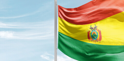 Bolivia national flag with mast at light blue sky.
