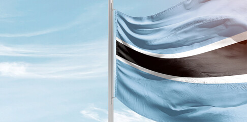 Botswana national flag with mast at light blue sky.