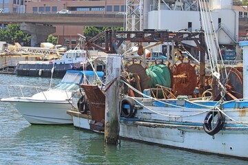 The back of an old fishing trawler and a speed boat. Docked at sydney fish markets