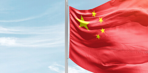 China national flag with mast at light blue sky.