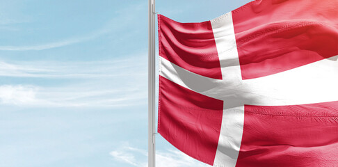 Denmark national flag with mast at light blue sky.