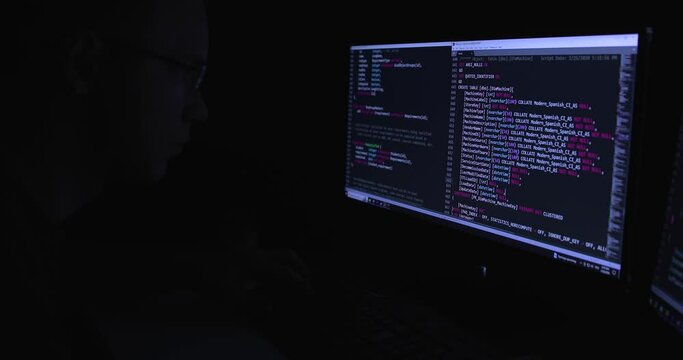 Two computer monitors displaying lines of code. Developer writing code