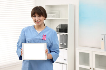 Mammologist with pink ribbon showing tablet in hospital, space for text. Breast cancer awareness