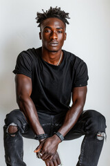 Modelo masculino negro de 22 años, con un aspecto natural, lleva jeans negros y una camiseta negra. La sesión fotográfica se realiza con un fondo blanco y se incluyen tomas de cuerpo entero con poses 