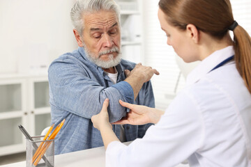Arthritis symptoms. Doctor examining patient's elbow in hospital