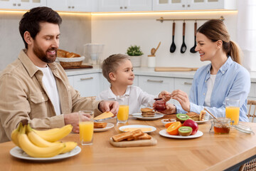 Happy family having breakfast at table in kitchen